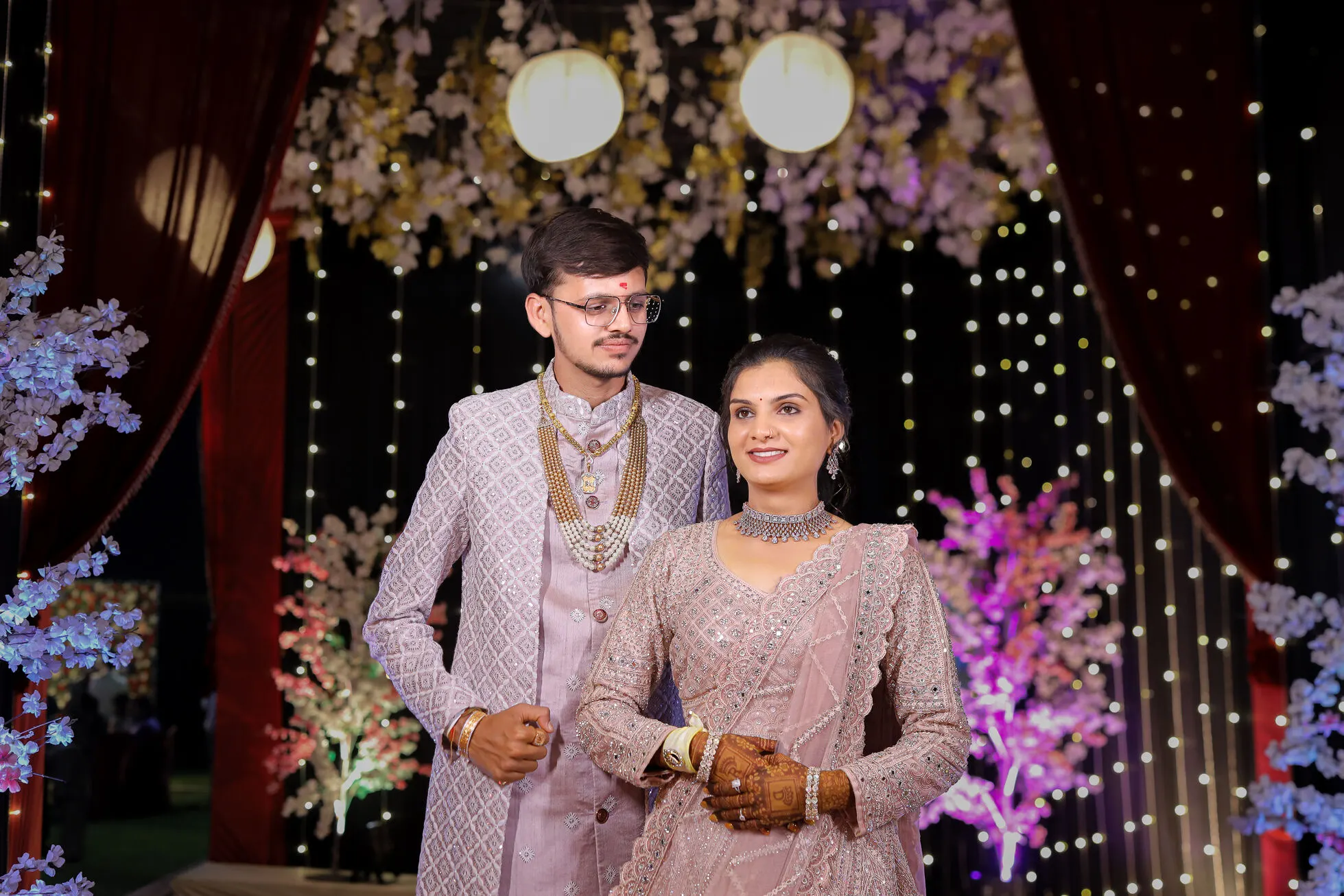 Indian wedding couple posing on decorated stage, reception photography Rajkot, elegant bridal and groom attire